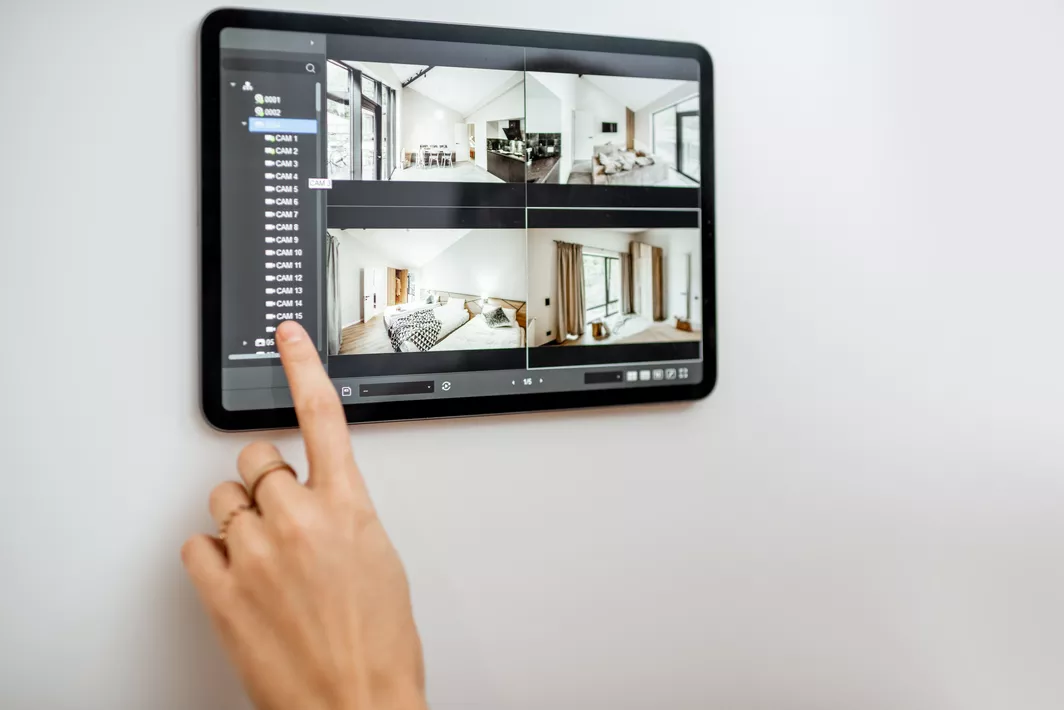 A woman’s finger touching a smart home device with video surveillance footage.
