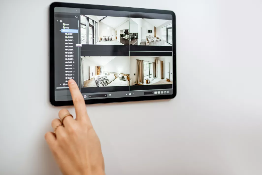 A woman’s finger touching a smart home device with video surveillance footage.