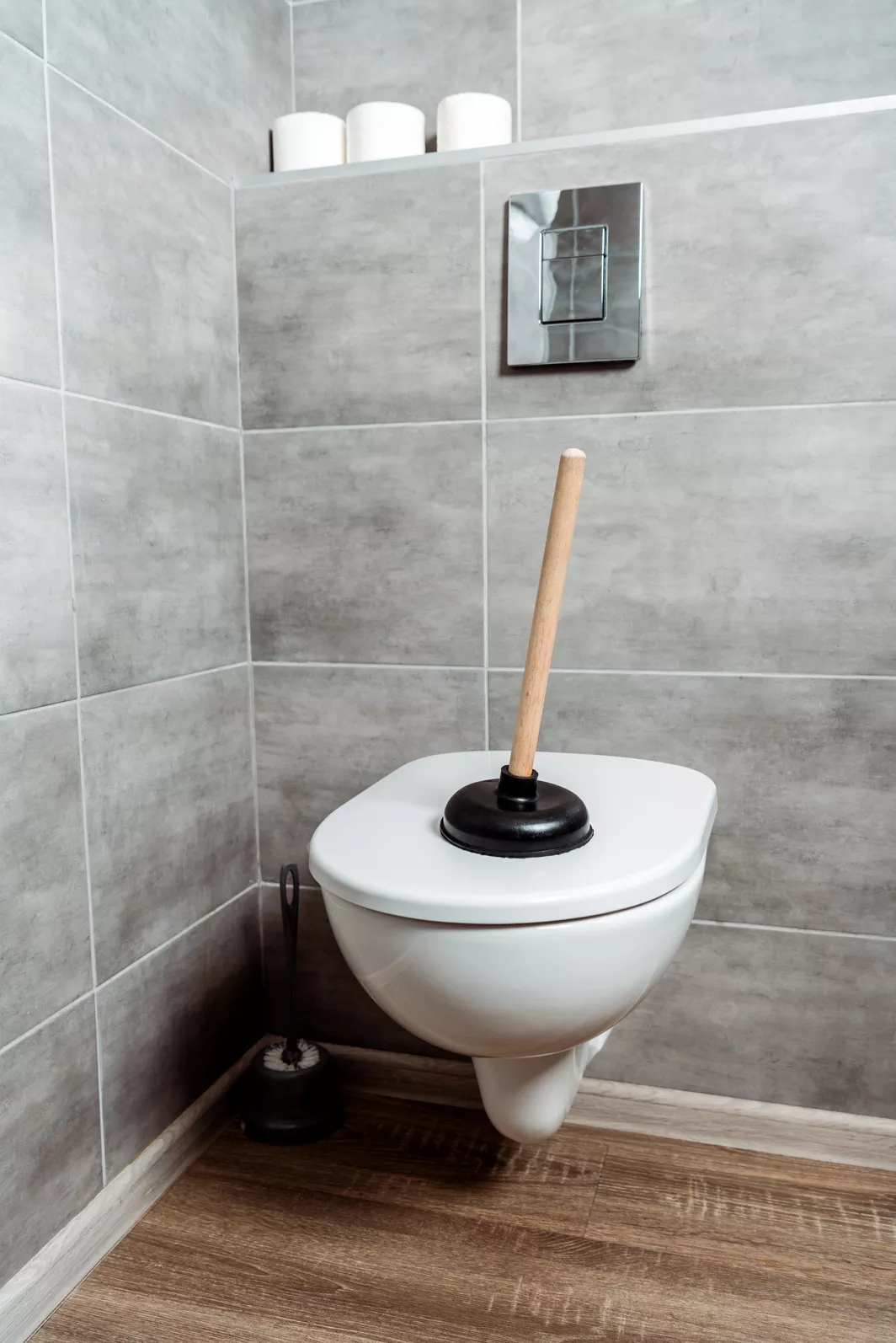 A black plunger suctioned to the top lid of a white porcelain toilet.
