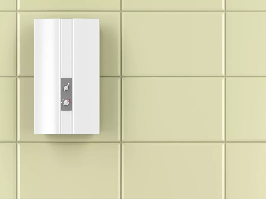 A tankless water heater affixed to square tiled wall.