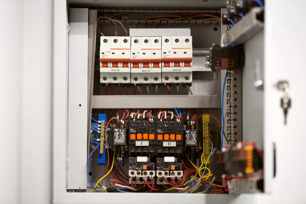 An opened electrical panel box showing various exposed wires and switches