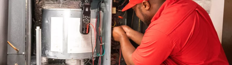 A service worker adjusts wires on a furnace.