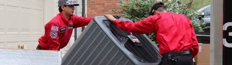 Two service workers install a large AC unit